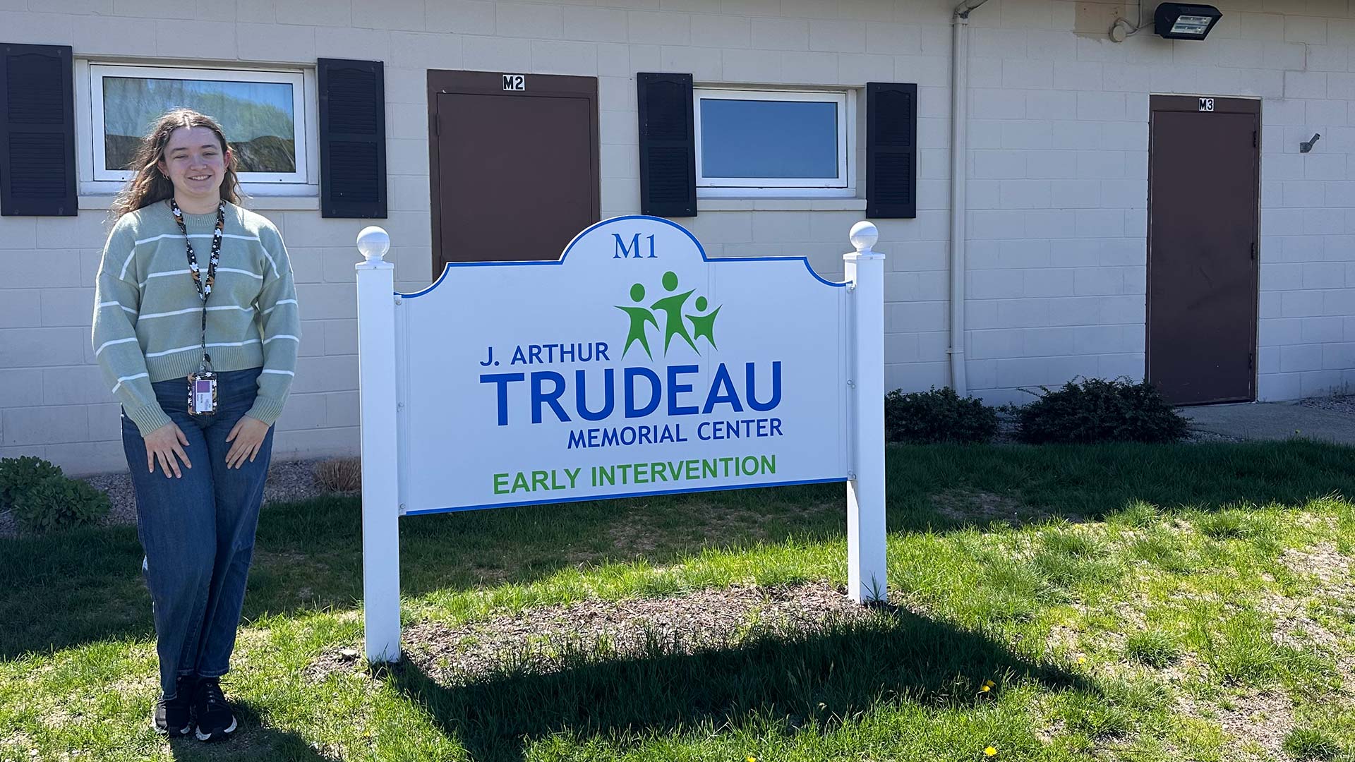 Riley Filiatreault '28 stands with the sign for the J. Arthur Trudeau Memorial Center